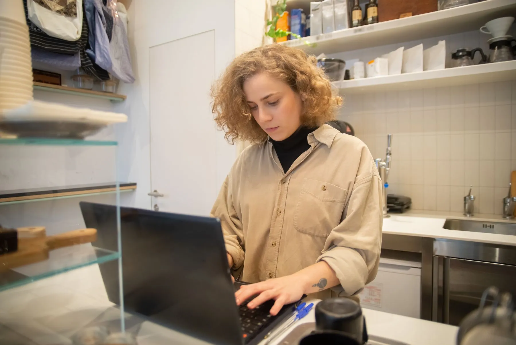 A café owner working at her laptop behind the counter